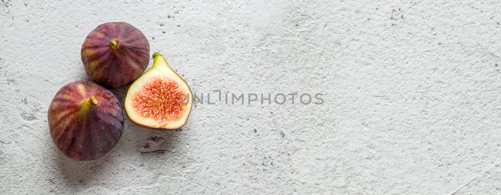 View of whole and cut organic figs on stone table