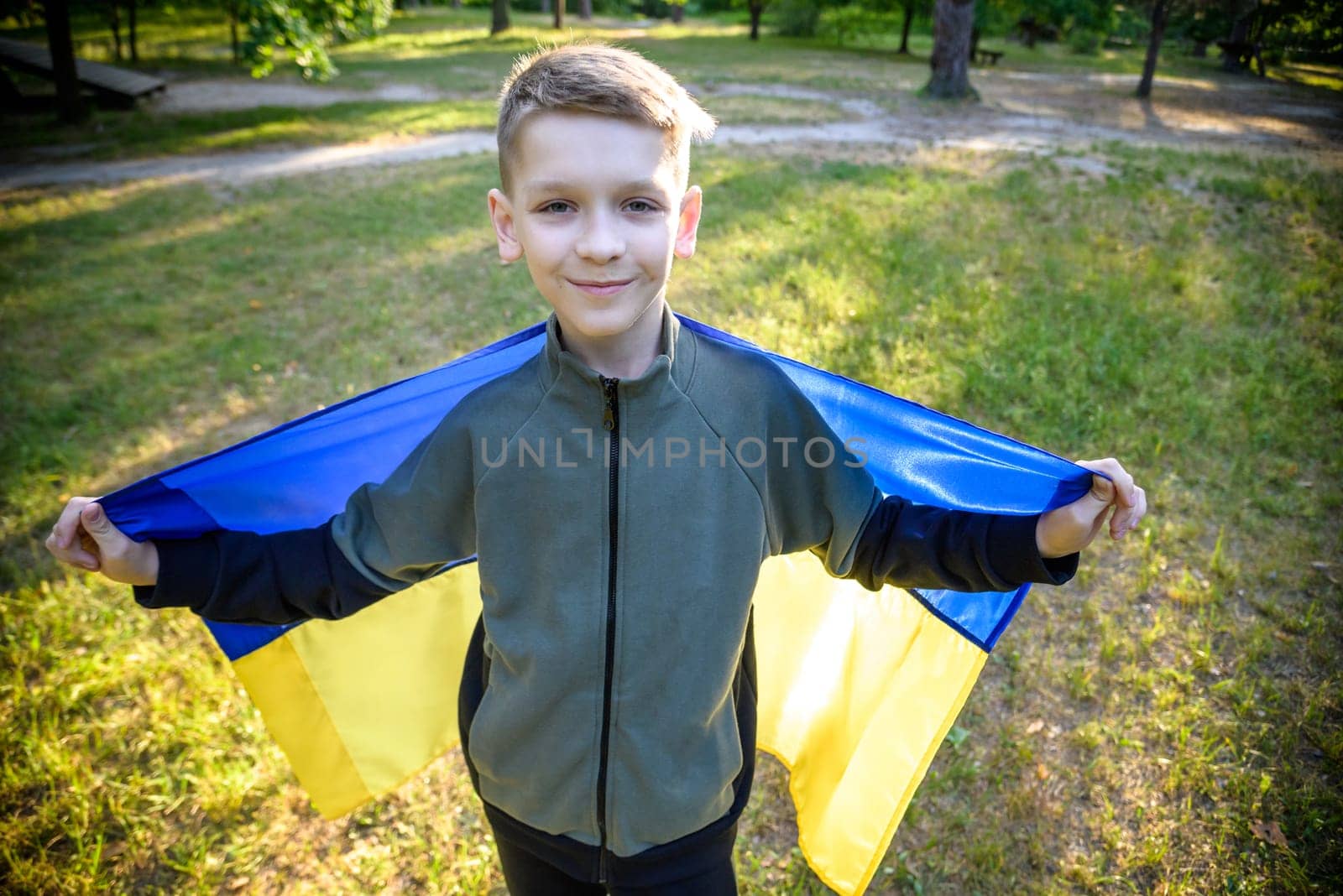 Pray for Ukraine. boy with Ukrainian flag running the summer park. Little kid waving national flag praying for peace. Happy child celebrating Independence Day.