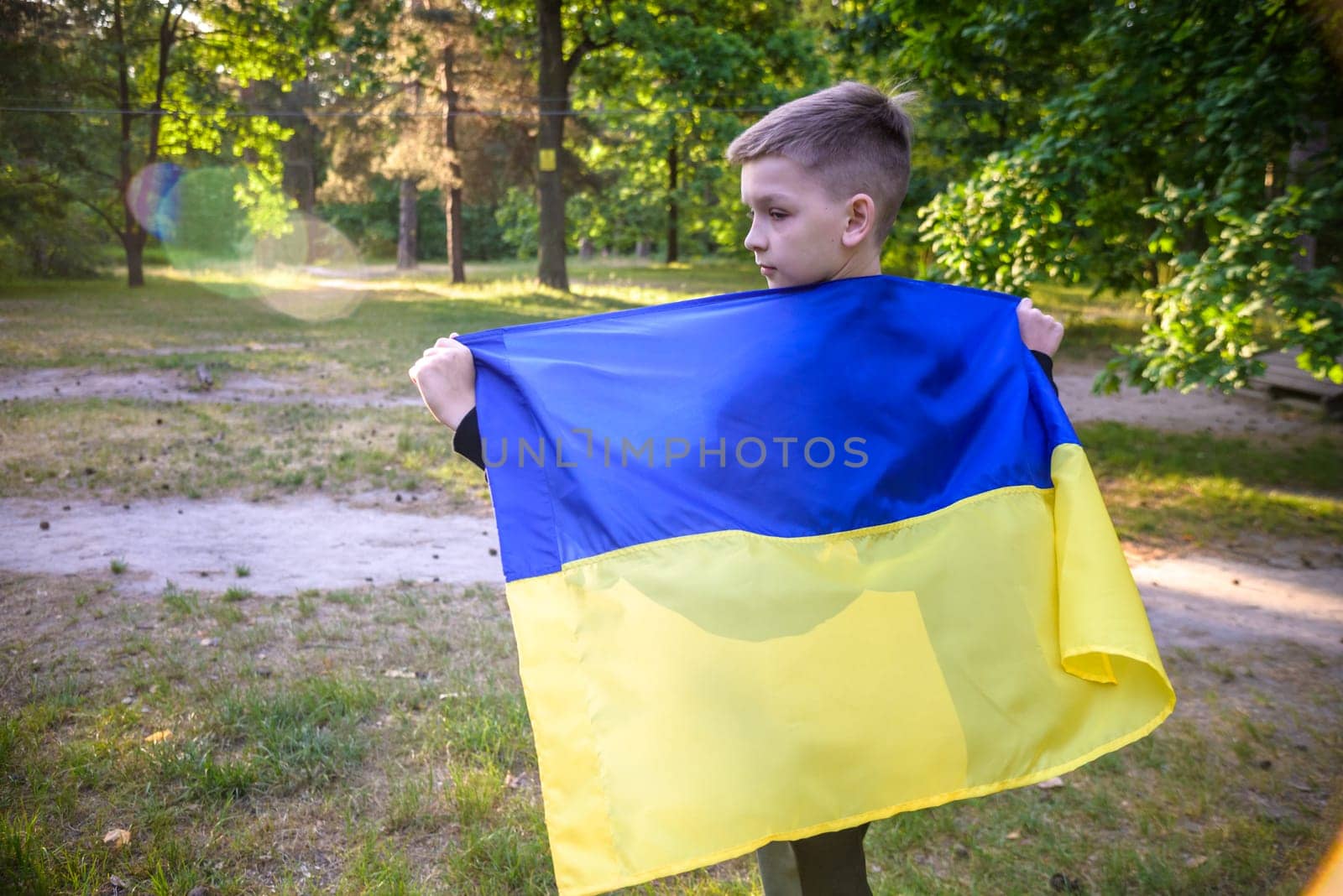 Pray for Ukraine. boy with Ukrainian flag running the summer park. Little kid waving national flag praying for peace. Happy child celebrating Independence Day.