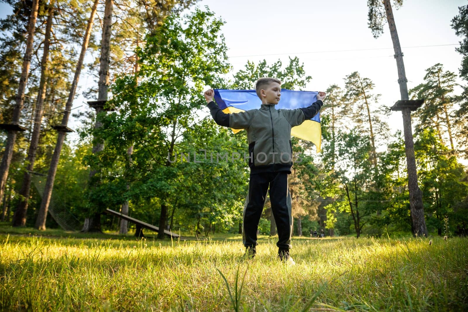 Pray for Ukraine. boy with Ukrainian flag running the summer park. Little kid waving national flag praying for peace. Happy child celebrating Independence Day.