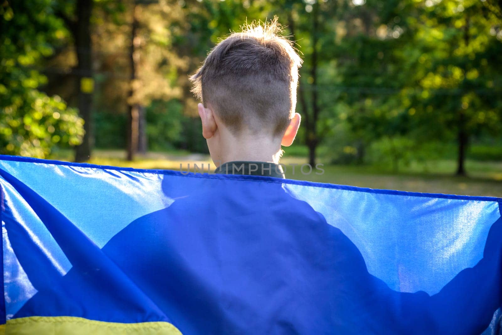 Pray for Ukraine. boy with Ukrainian flag running the summer park. Little kid waving national flag praying for peace. Happy child celebrating Independence Day.