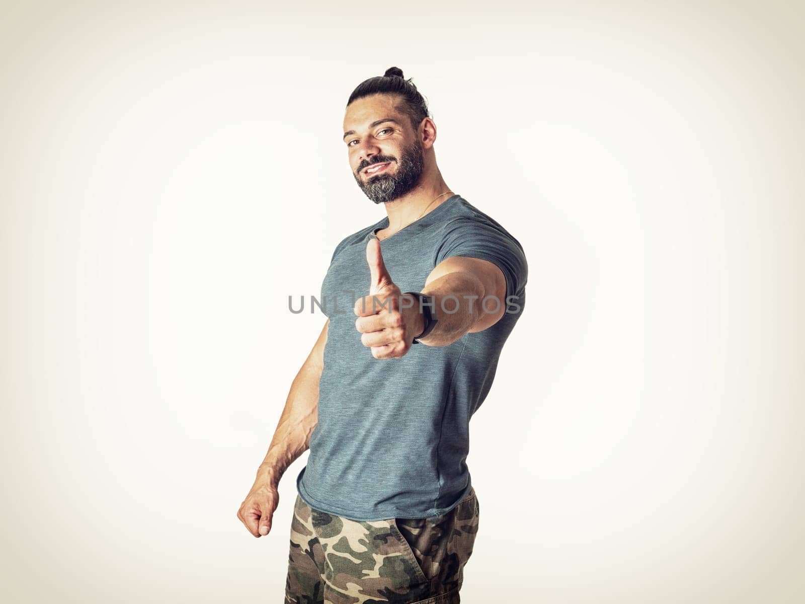 A man giving a thumbs up while wearing camouflage shorts