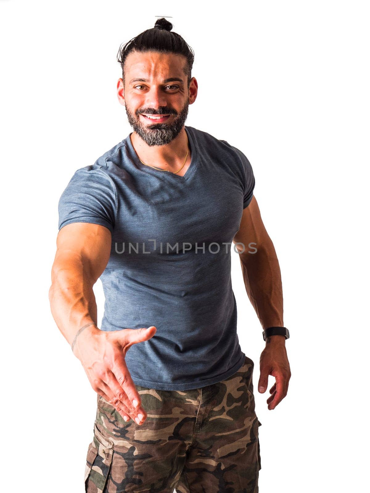 A man with a goatee and a beard is reaching his hand for a friendly handshake directed to the viewer, with a smile