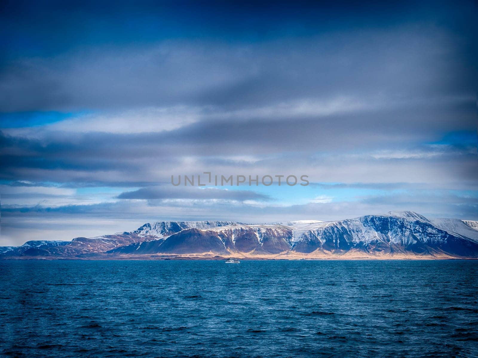 A large body of water with mountains in the background. Photo of a stunning landscape with mountains reflected in a calm body of water in Iceland