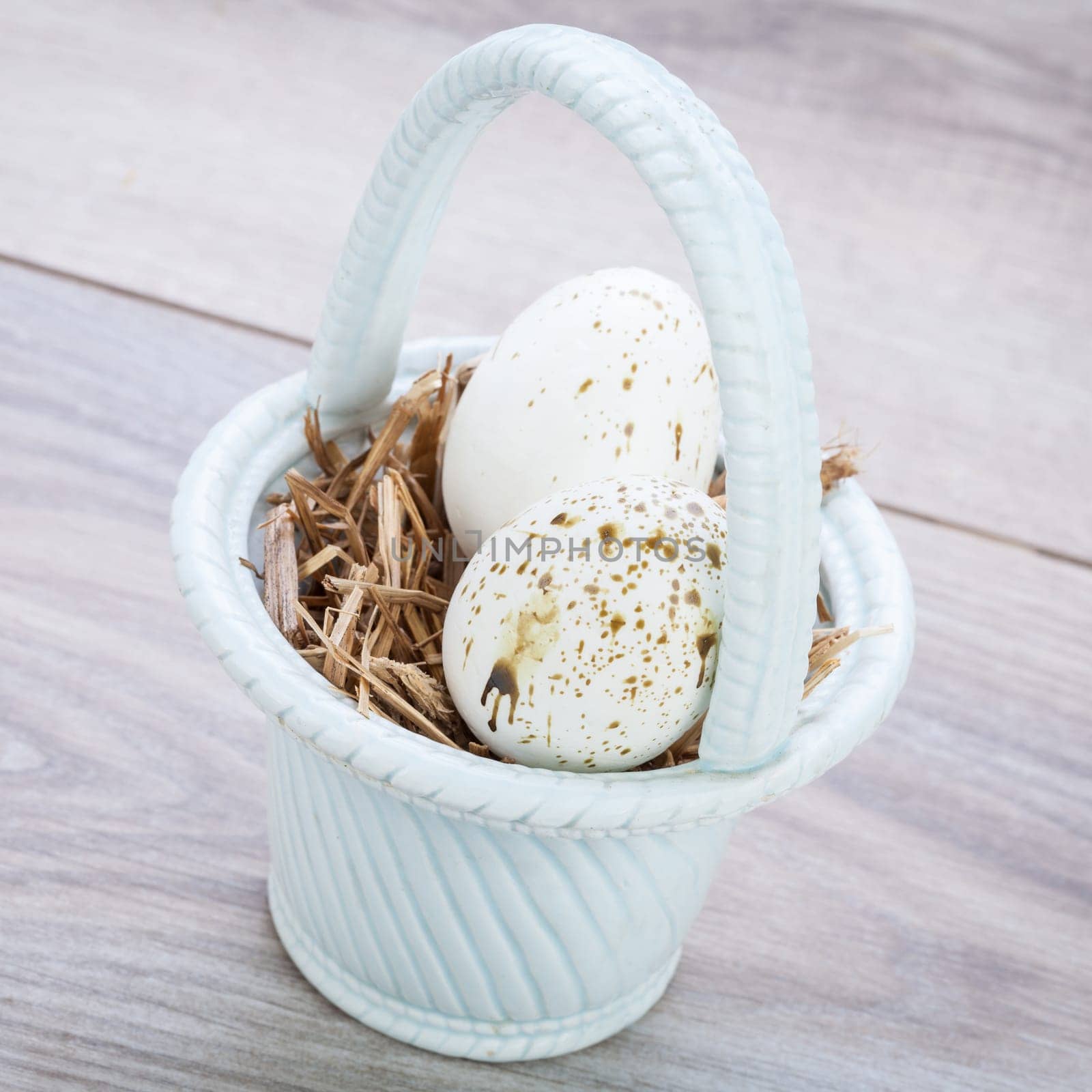 Three colorful bright Easter eggs in a basket on a wooden table Easter decoration custom spring festive