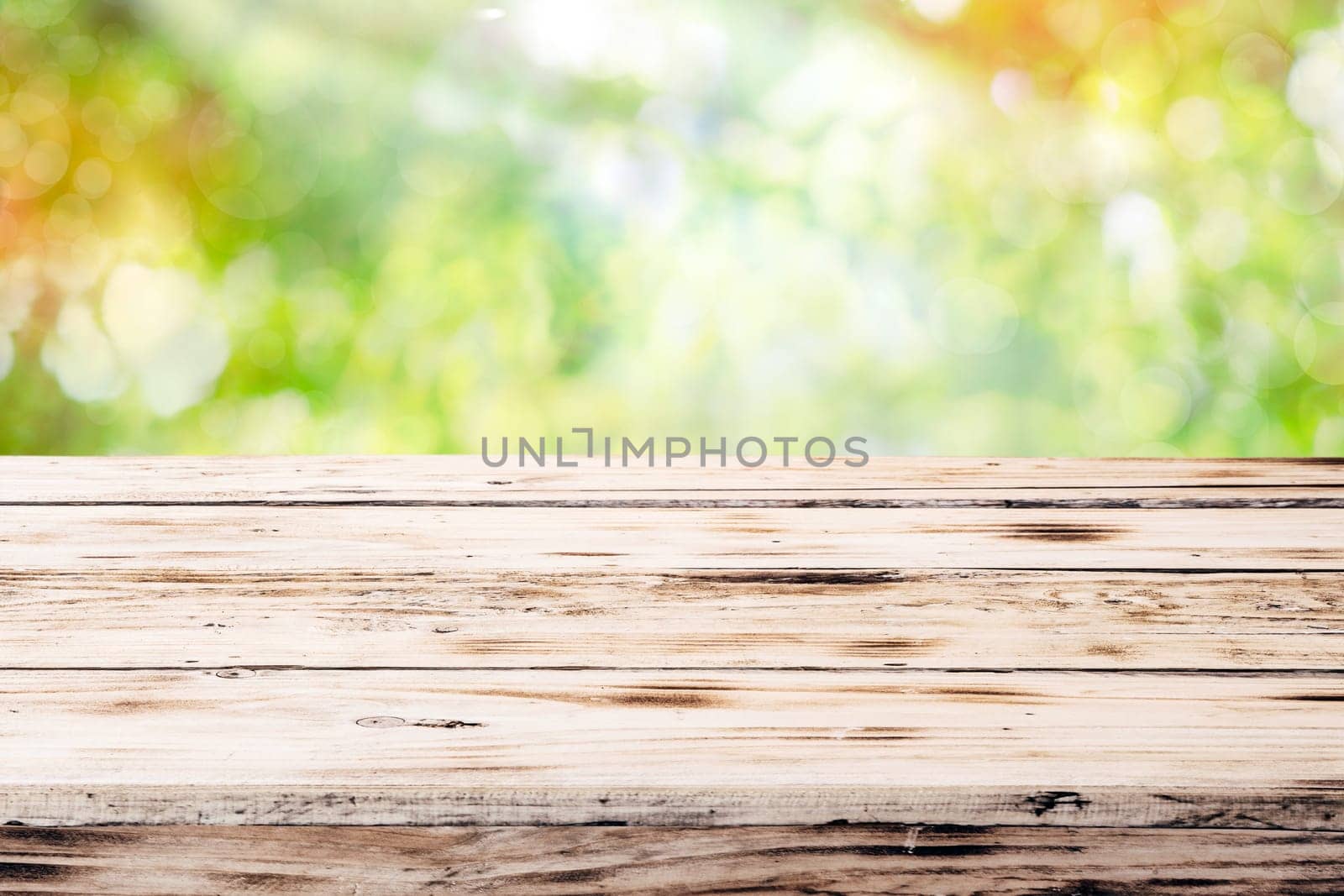 Old empty rustic grunge wooden table top against a blurred green blurred outdoor backgorund with copyspace