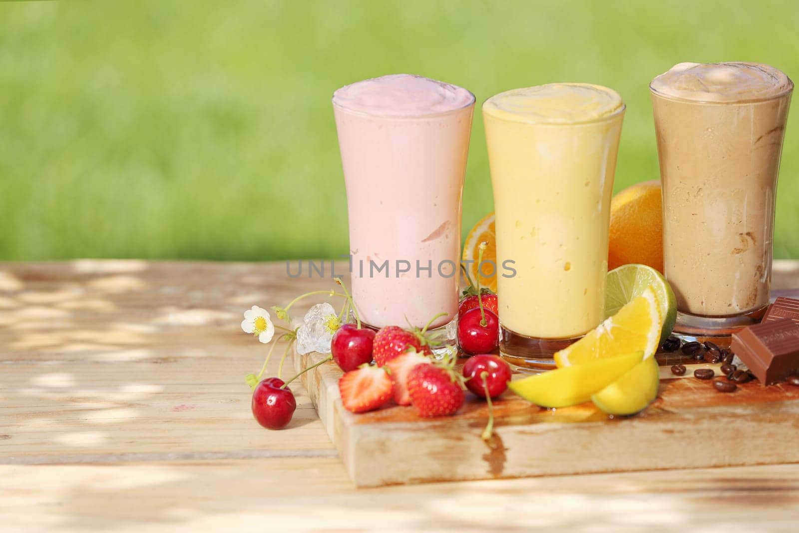 Three healthy smoothie milkshake drinks in tall glasses, natural tones