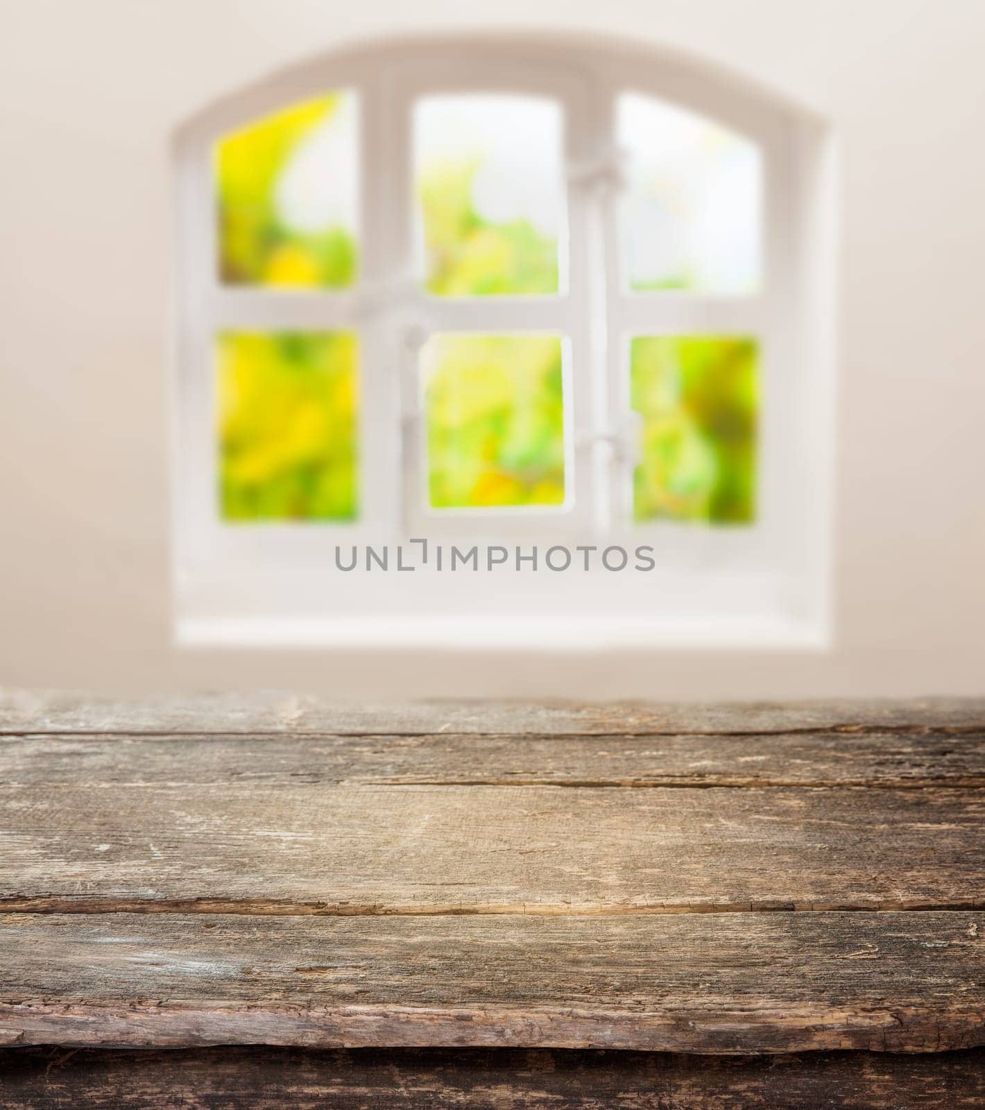 Old grunge table with a weathered rustic wooden top in front of a sunny cottage pane window in a country kitchen with space for your ingredients or product