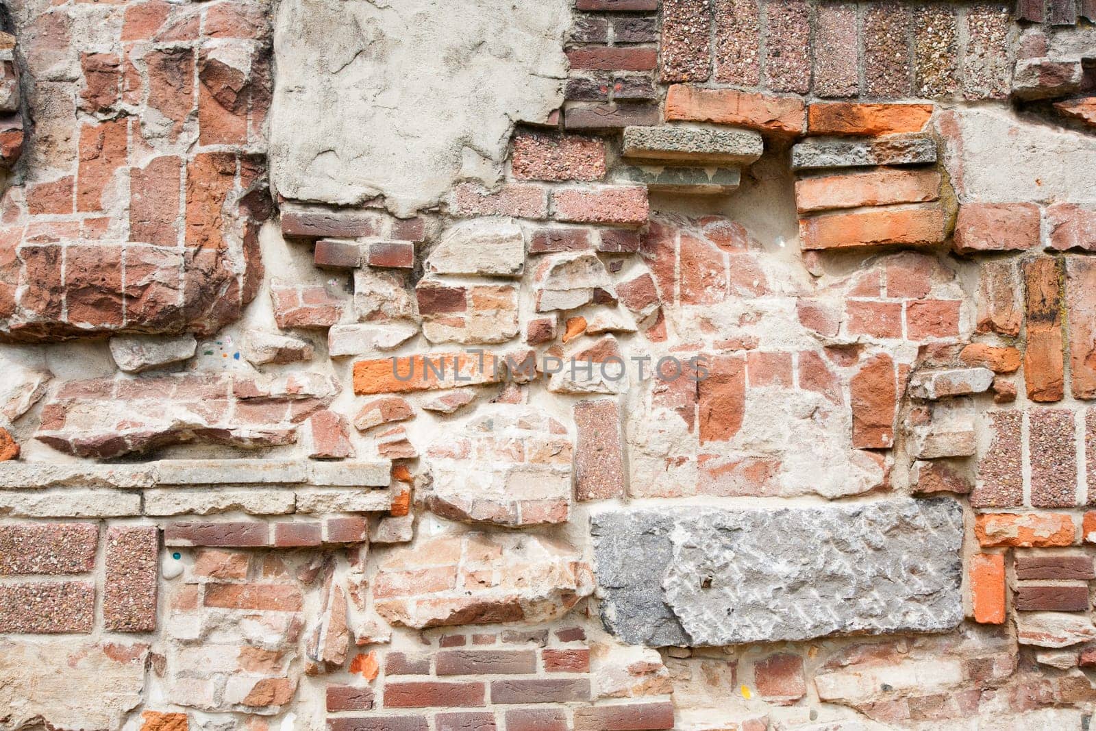 Stone wall made of a variety of rocks and bricks.