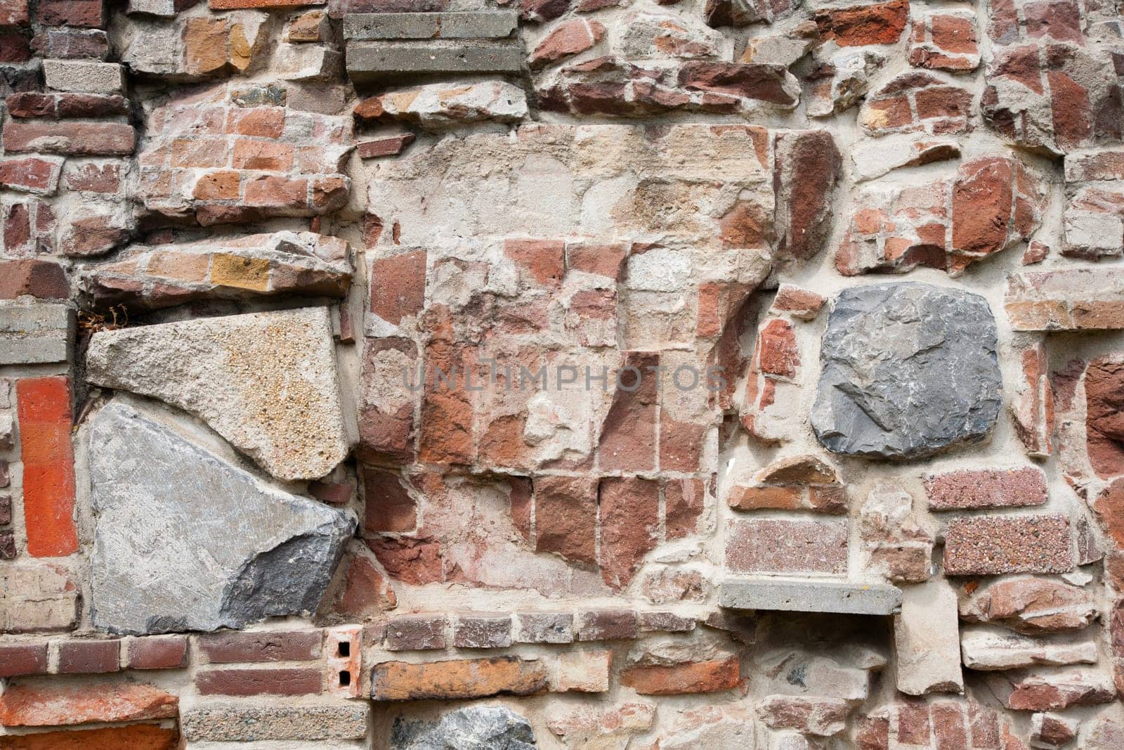 Stone wall made of a variety of rocks and bricks.