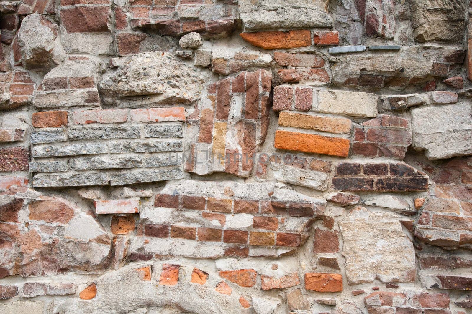 Stone wall made of a variety of rocks and bricks.