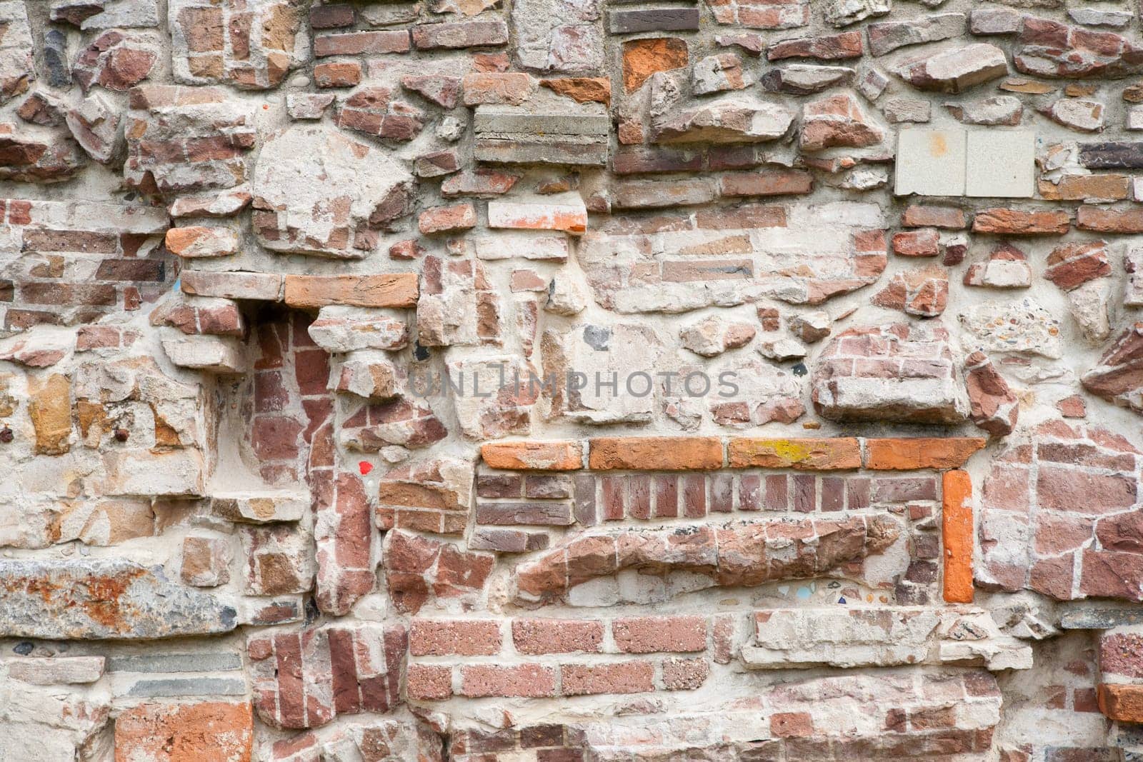 Stone wall made of a variety of rocks and bricks.