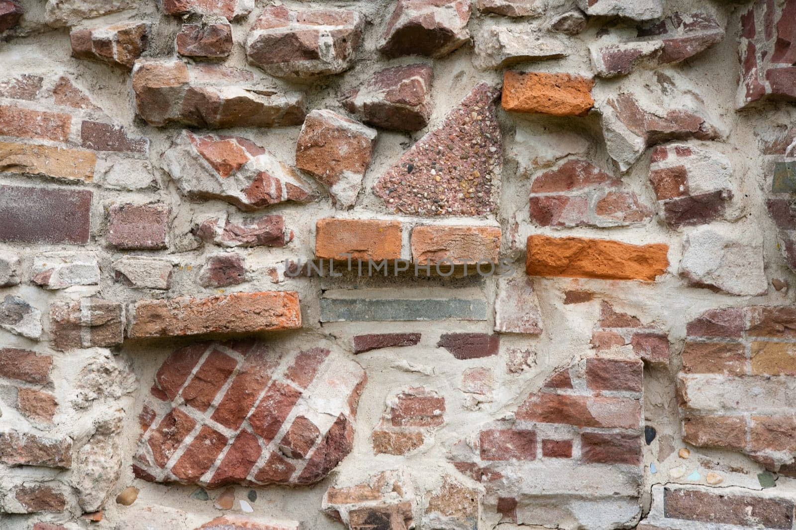 Stone wall made of a variety of rocks and bricks.