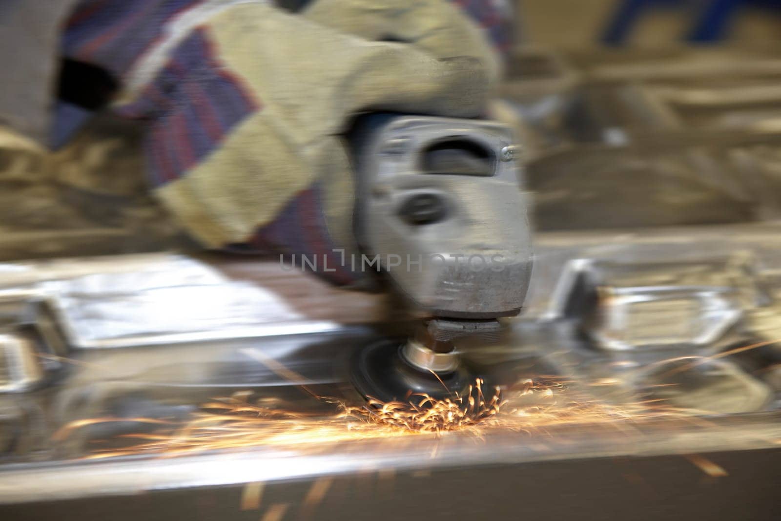 factory floor worker using a angle grinder on metal surface