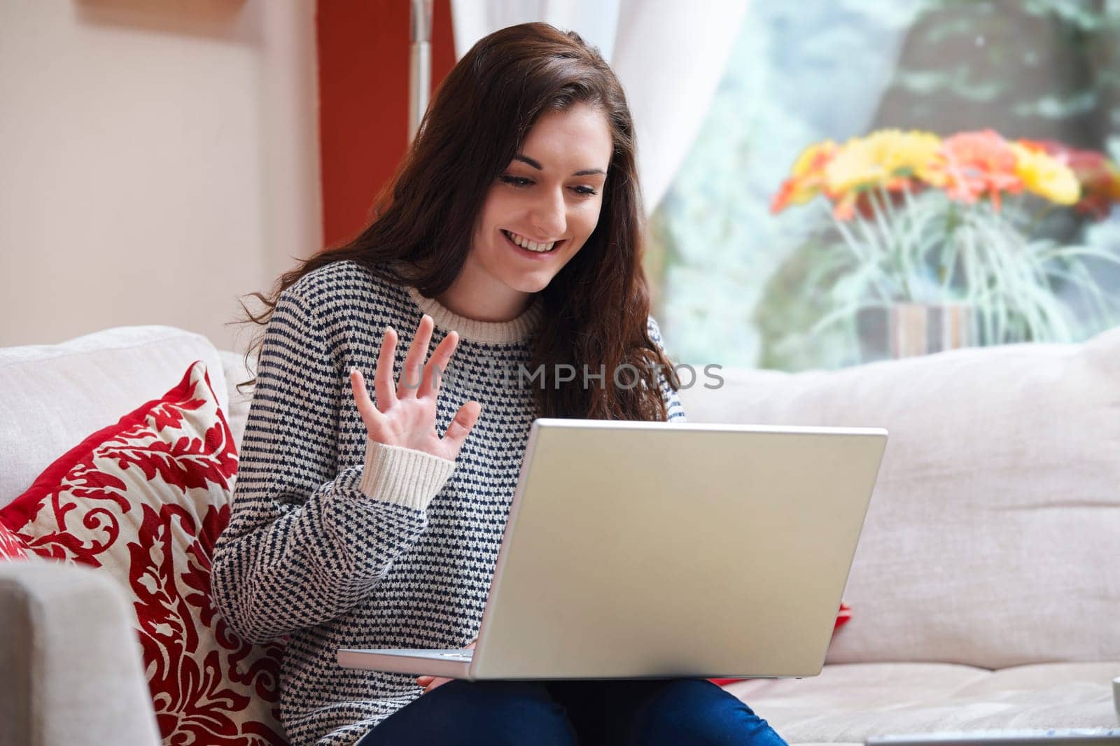 teenage girl waving at laptop while using webcam at home
