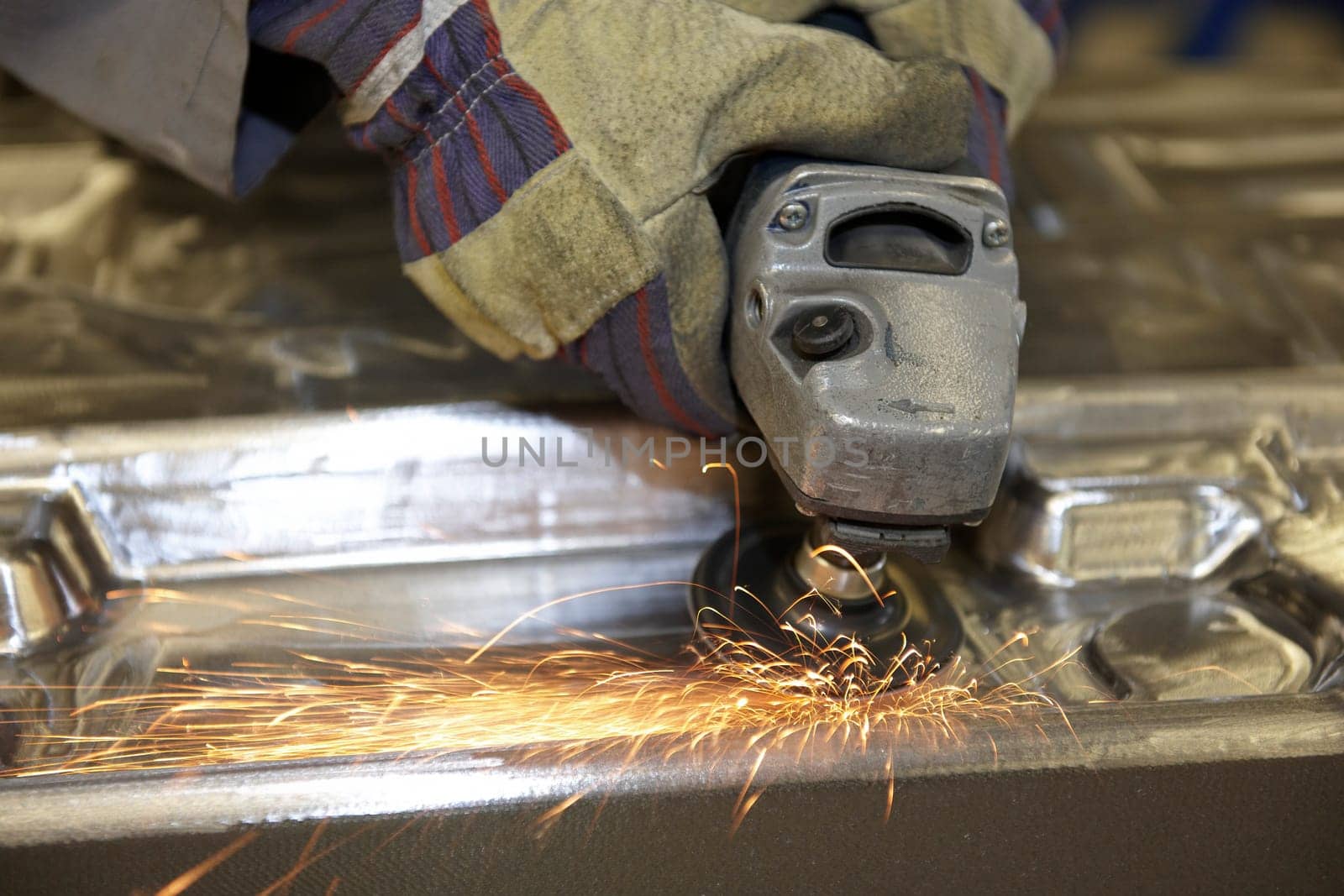 factory floor worker using a angle grinder on metal surface