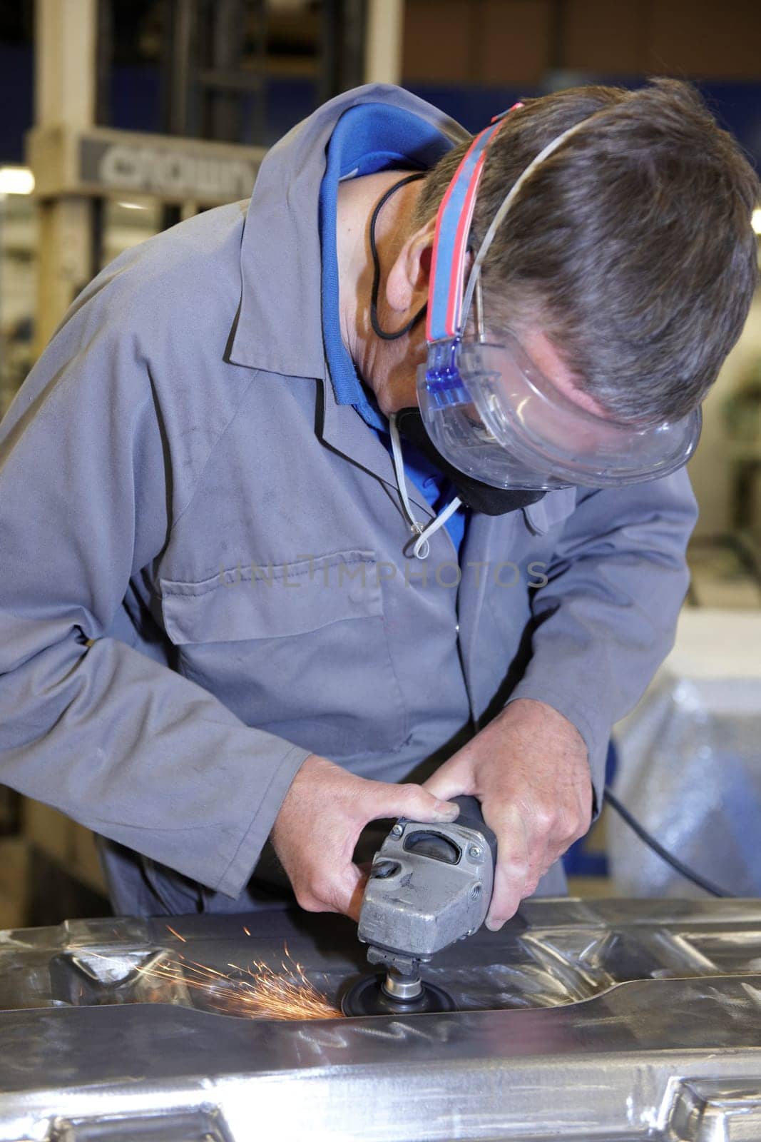 factory floor worker using a angle grinder on metal surface