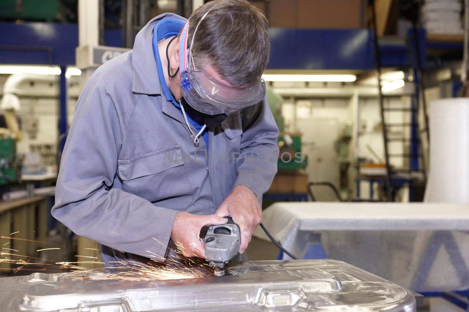 factory floor worker using a angle grinder on metal surface