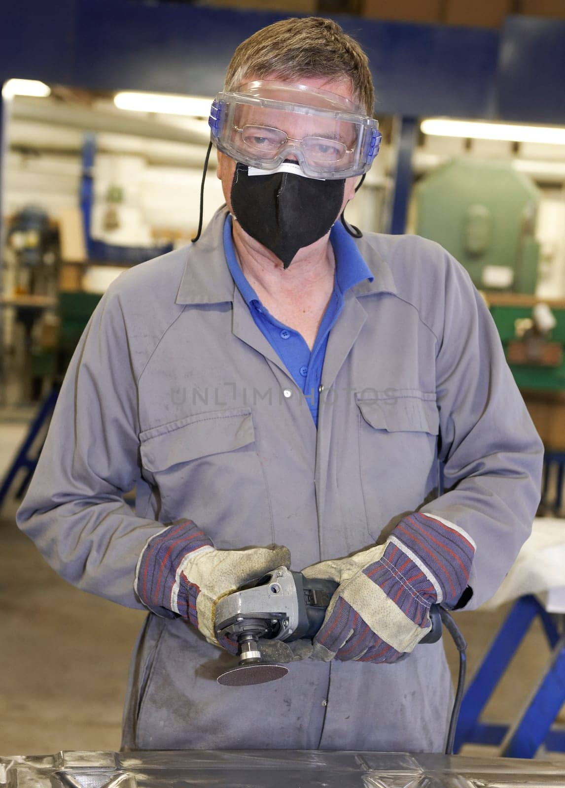 factory floor worker using a angle grinder on metal surface