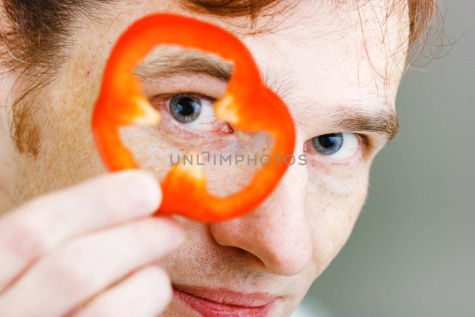 Young man with red pepper. Face close-up. humor