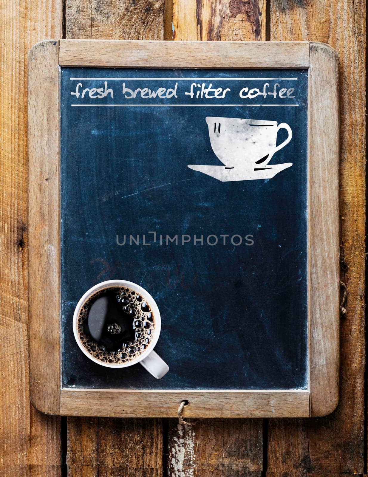 Fresh brewed filter coffee - handwritten on an old vintage school slate used as an advertising sign in a rustic coffee shop with a fresh cup of aromatic coffee in the bottom corner