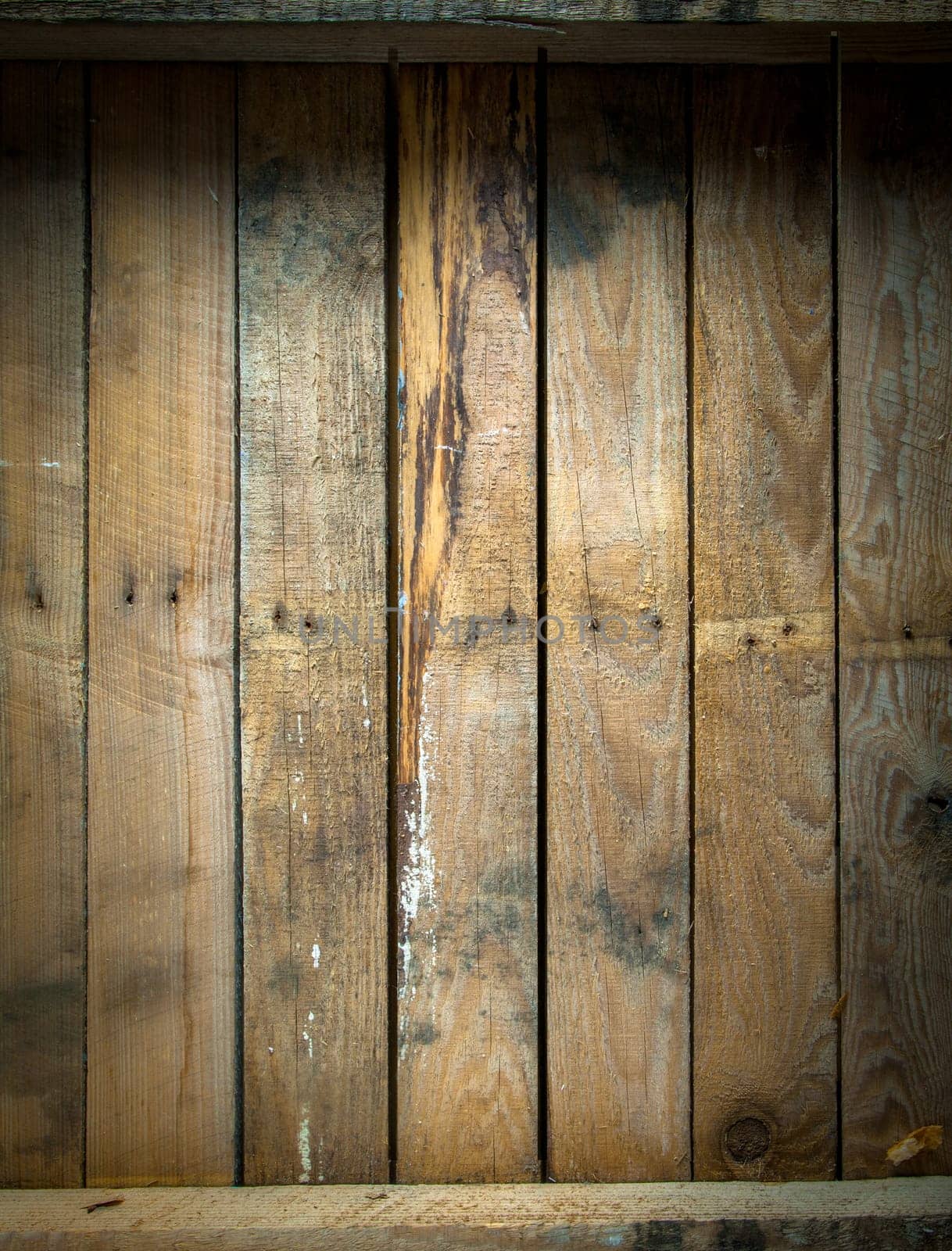 Background texture of a grungy stained and weathered wooden table top with a line of old nails and parallel vertical planks
