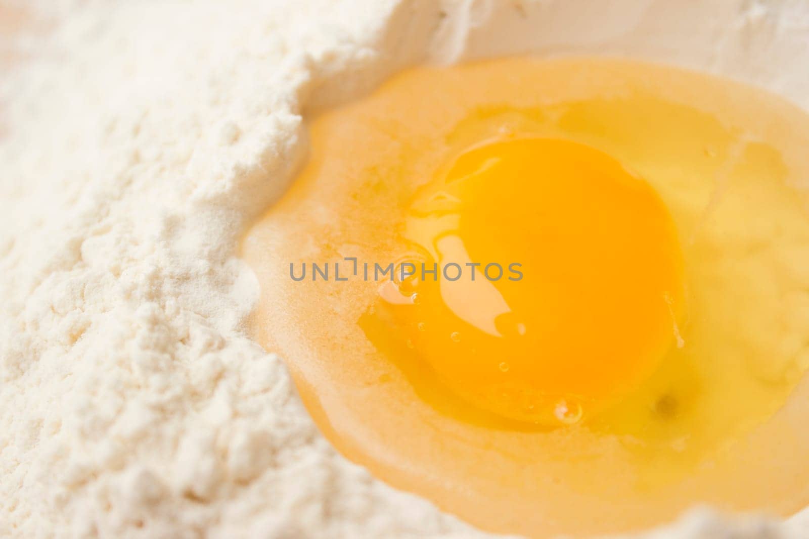 Flour on a wooden cutting board with a egg in the middle of it.