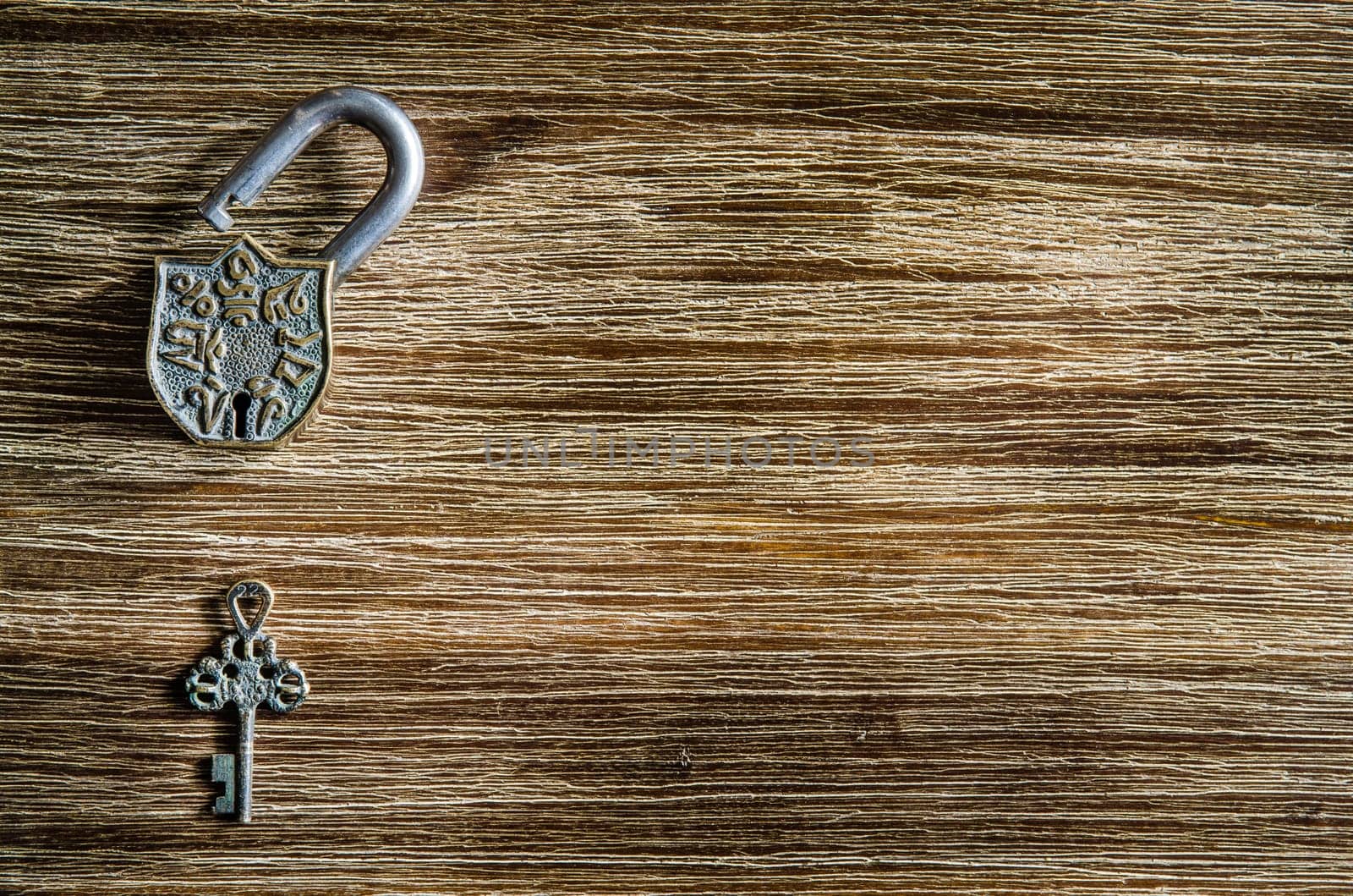 Open vintage padlock and old key on a wooden textured table