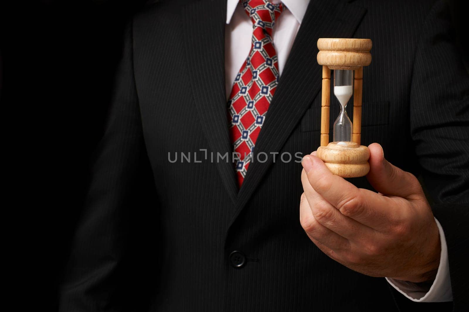 businessman holding hourglass towards camera with space for copy