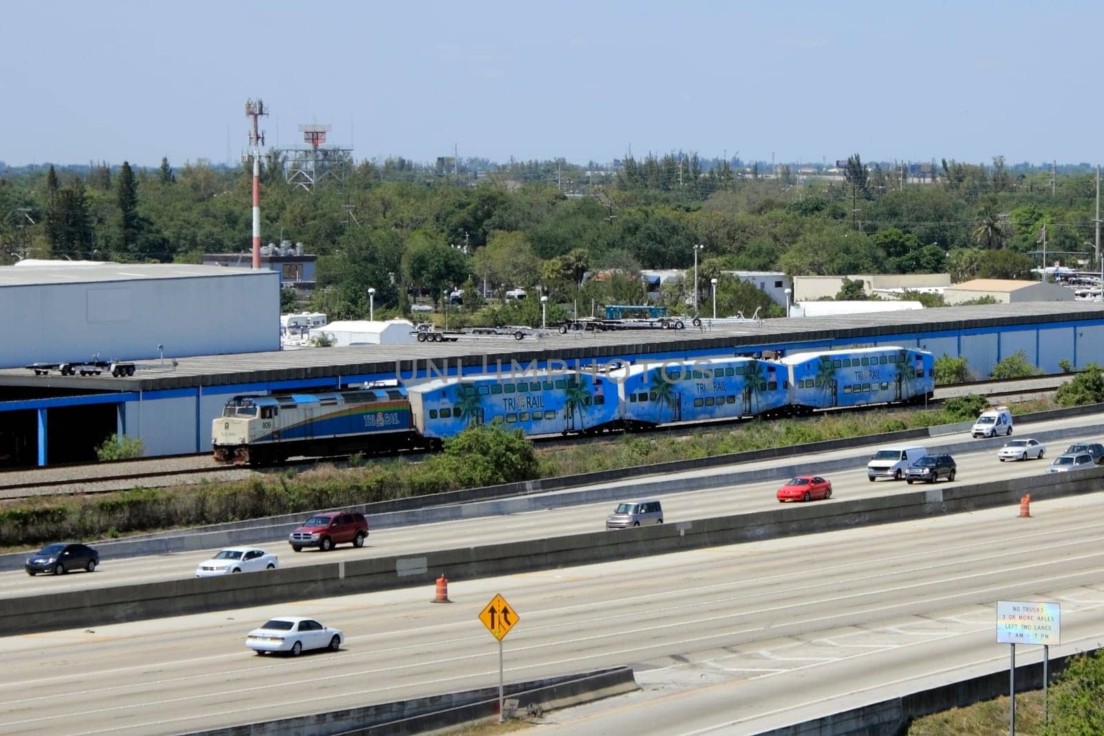 FORT LAUDERDALE, FLORIDA - MARCH 30, 2013: Tri-Rail engine and three passenger trains moving south next to I-95 Highway. This public transportation links three counties from Mangonia Park to Miami.