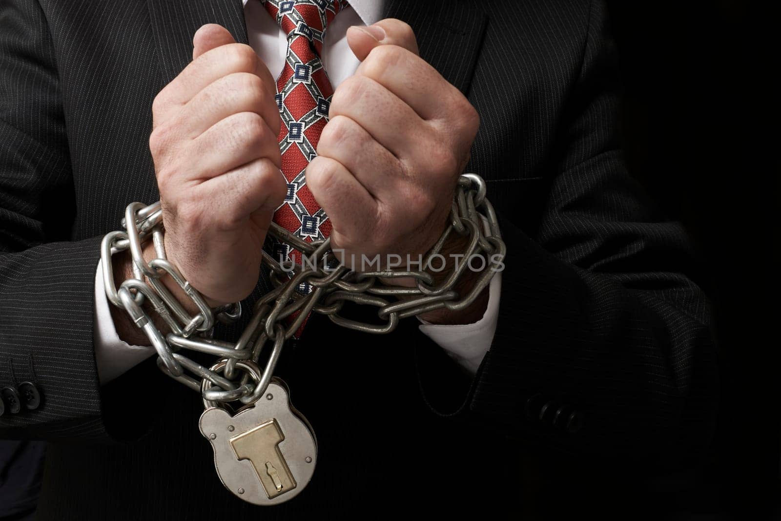 Close up of businessmans hands tied in heavy chains with padlock