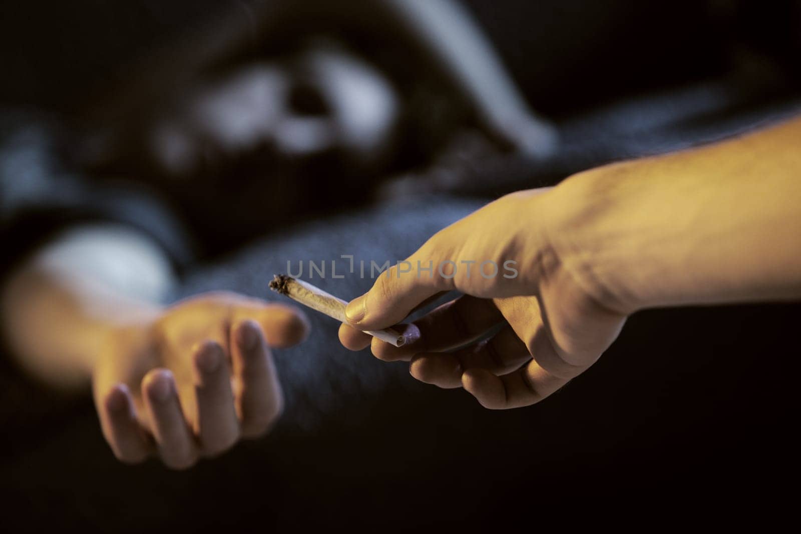 Close up of two young adults smoking a joint
