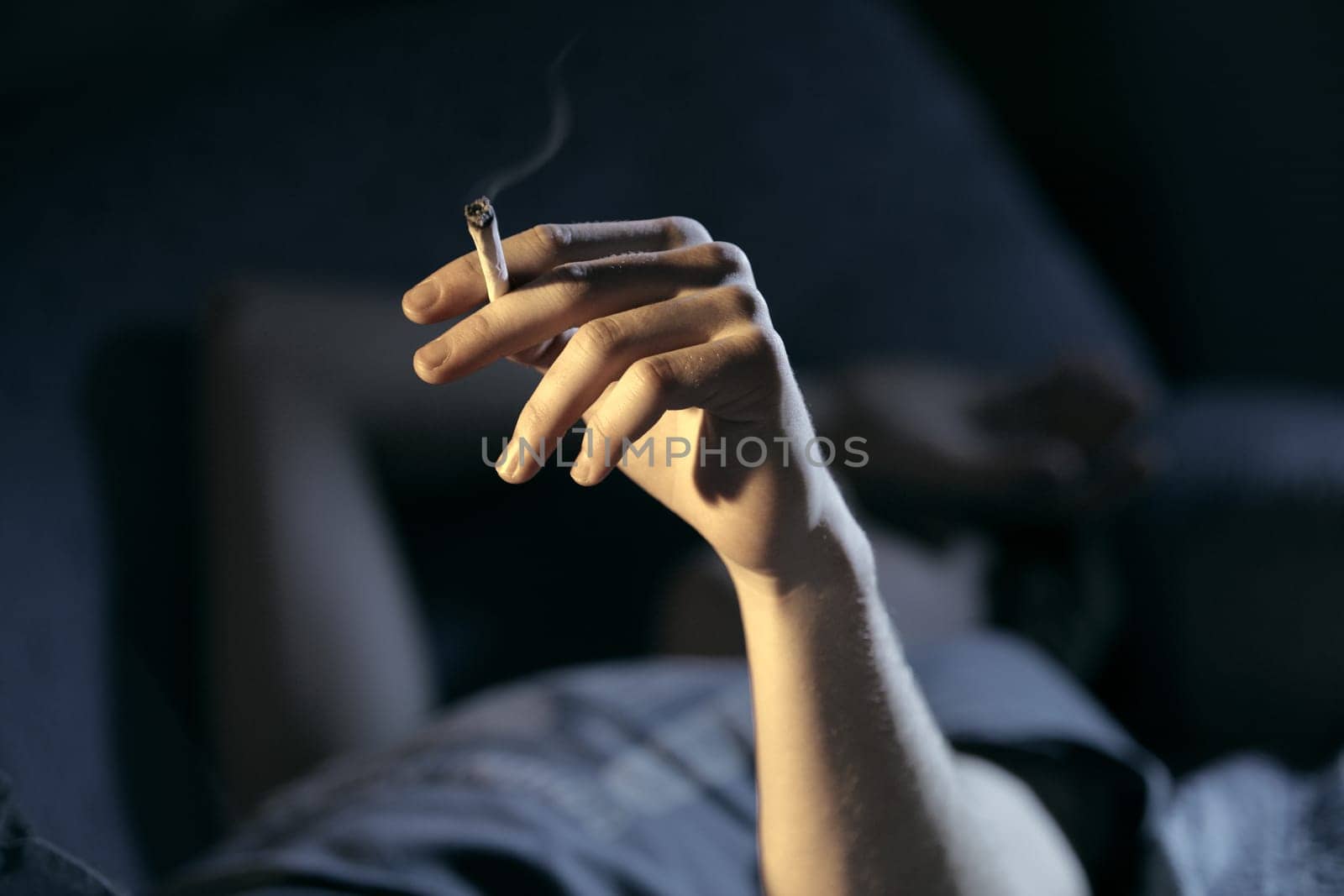 Close up of teenage boy smoking drugs lying on the couch