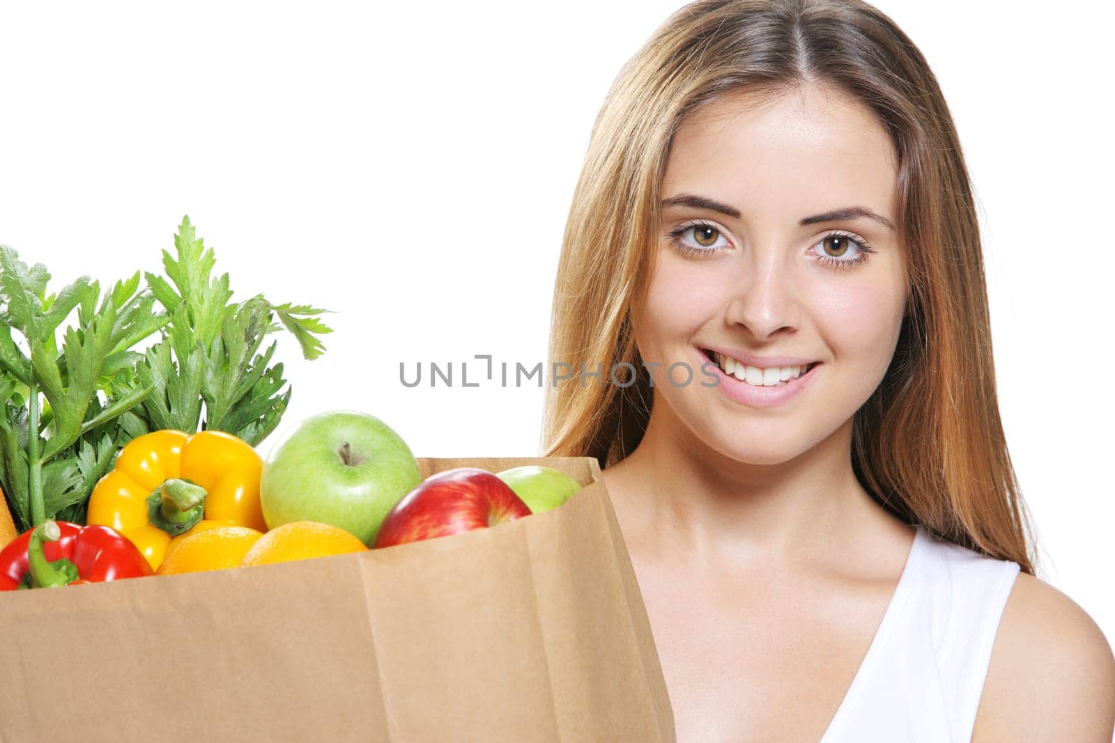Portrait of smiling young woman holding a shopping bag full of groceries on white background