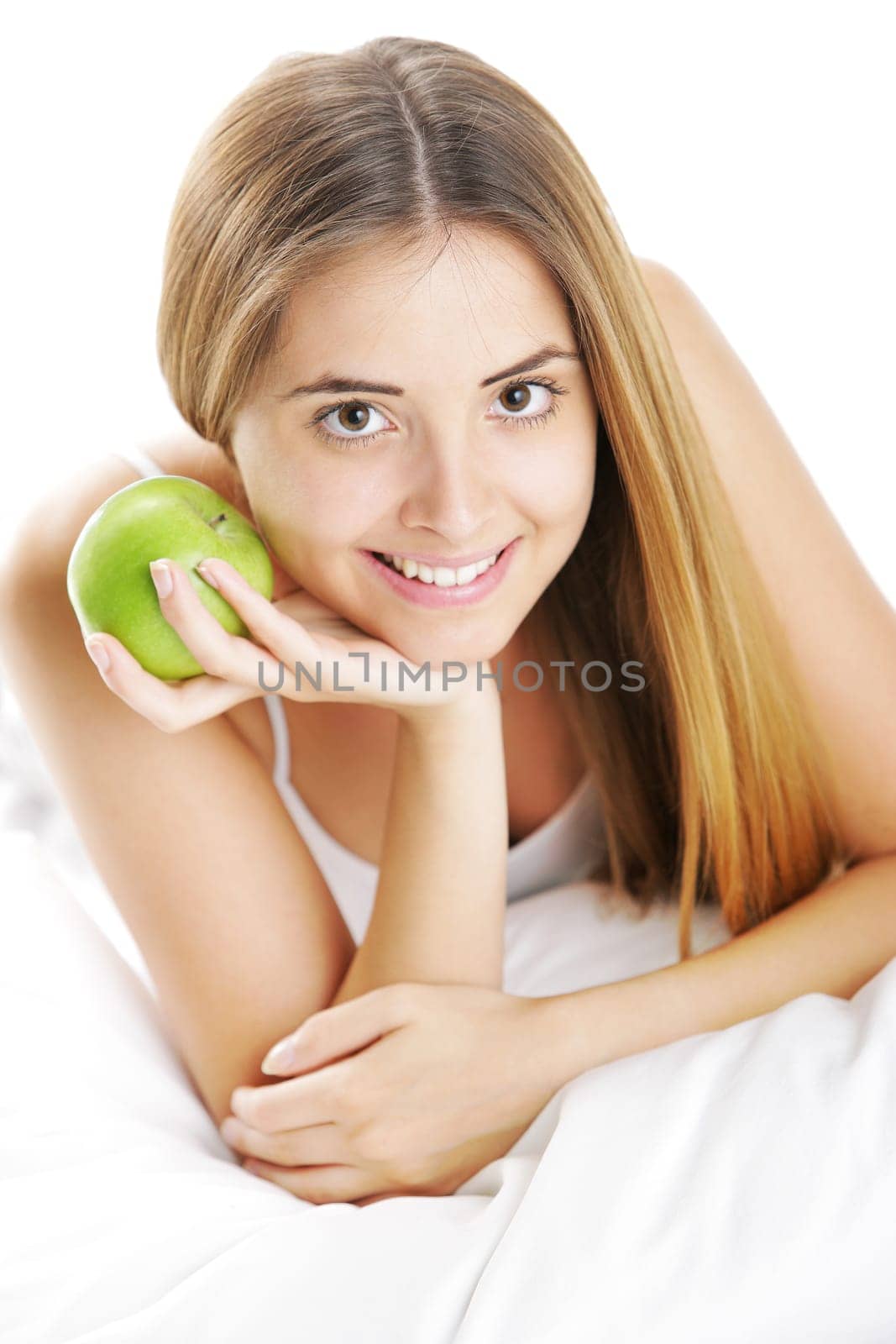 Smiling Young Woman Holding Apple in Bed