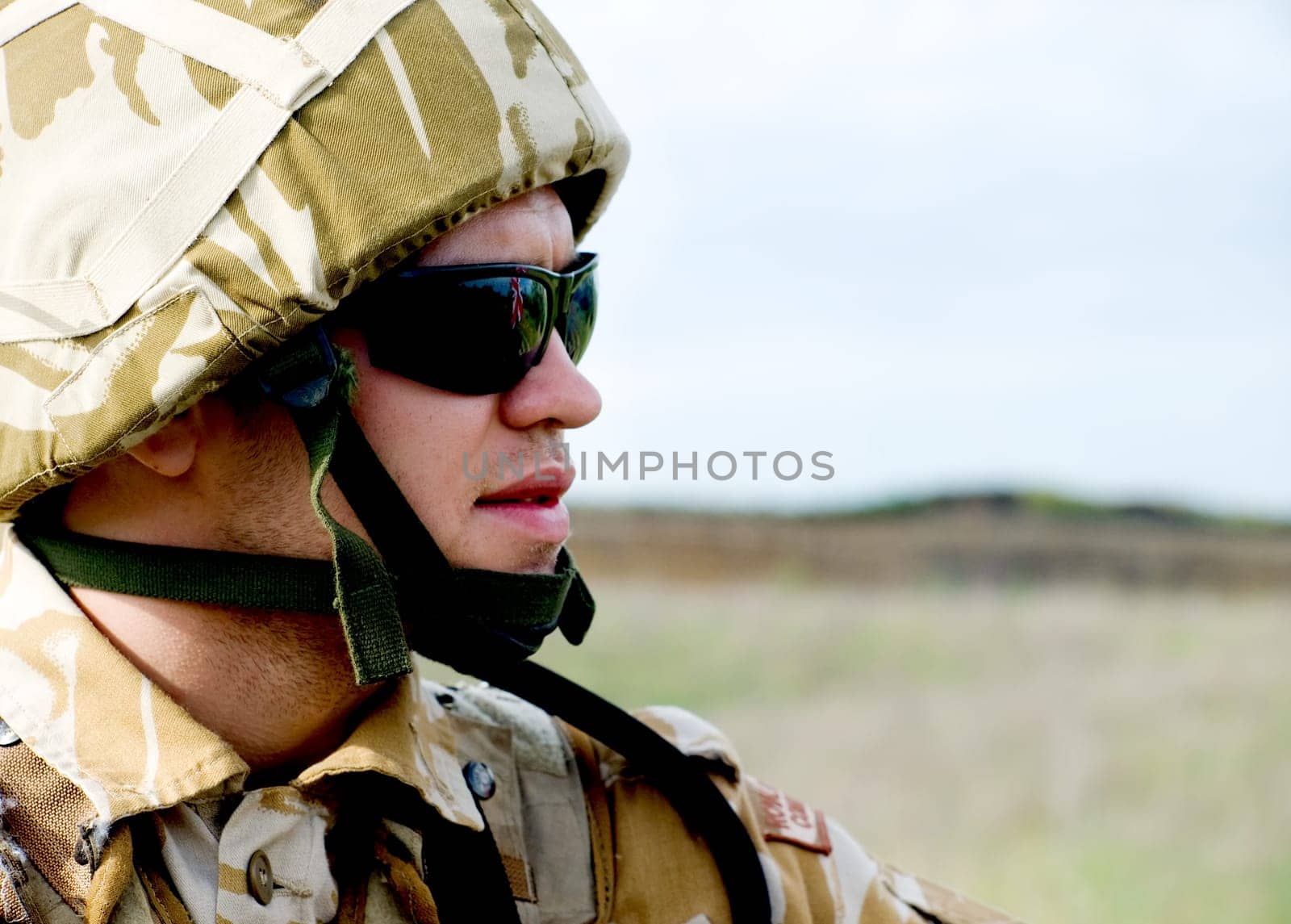 British soldier with the reflection of UK flag in glasses looking forward