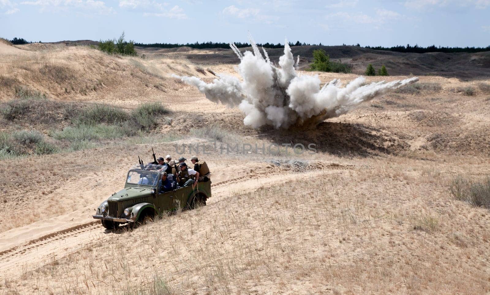 Large explosion near the car with soldiers in the desert