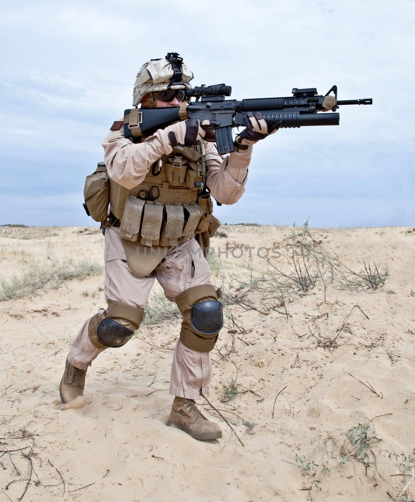US soldier runs through the desert shooting a gun with grenade launcher