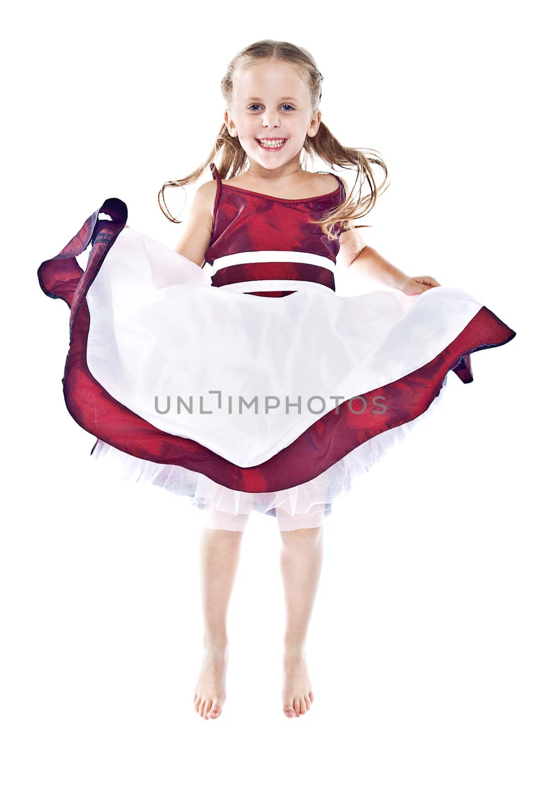Laughing little girl in red and white dress jumping and lifting up her skirt