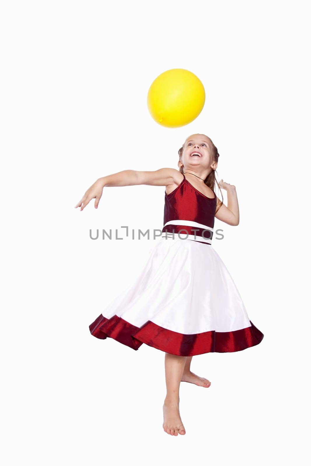 Laughing little girl in red and white dress playing with balloon