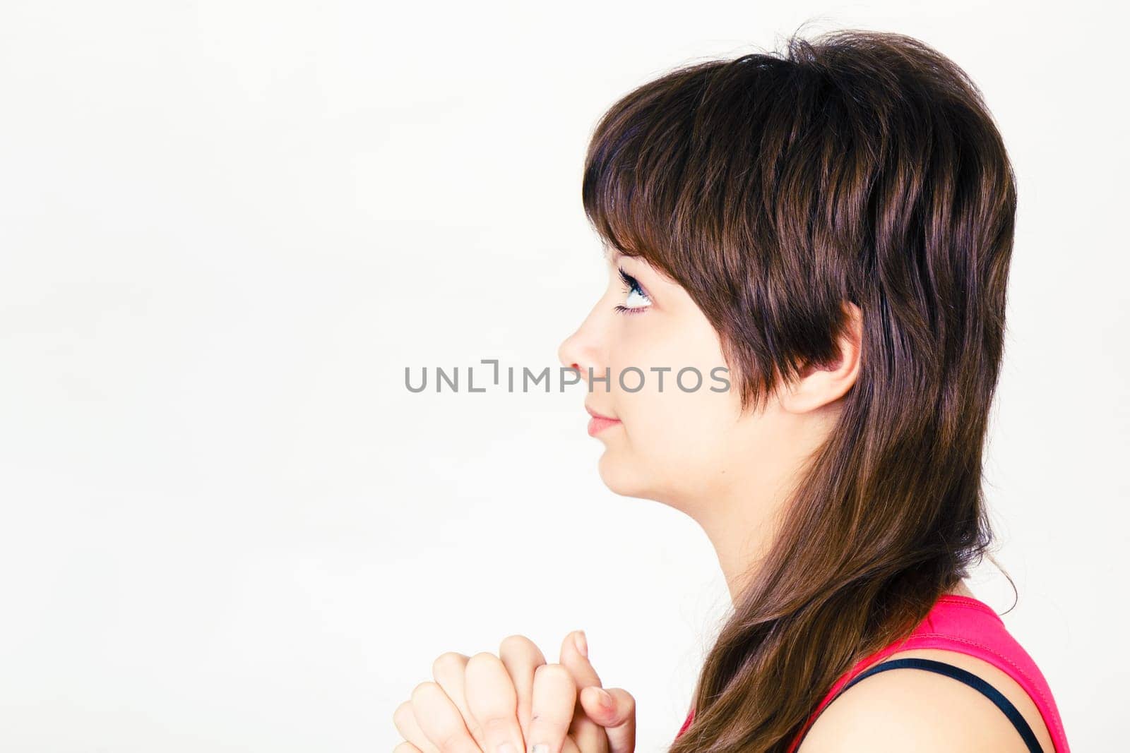 Young attractive girl praying with clasped hands together