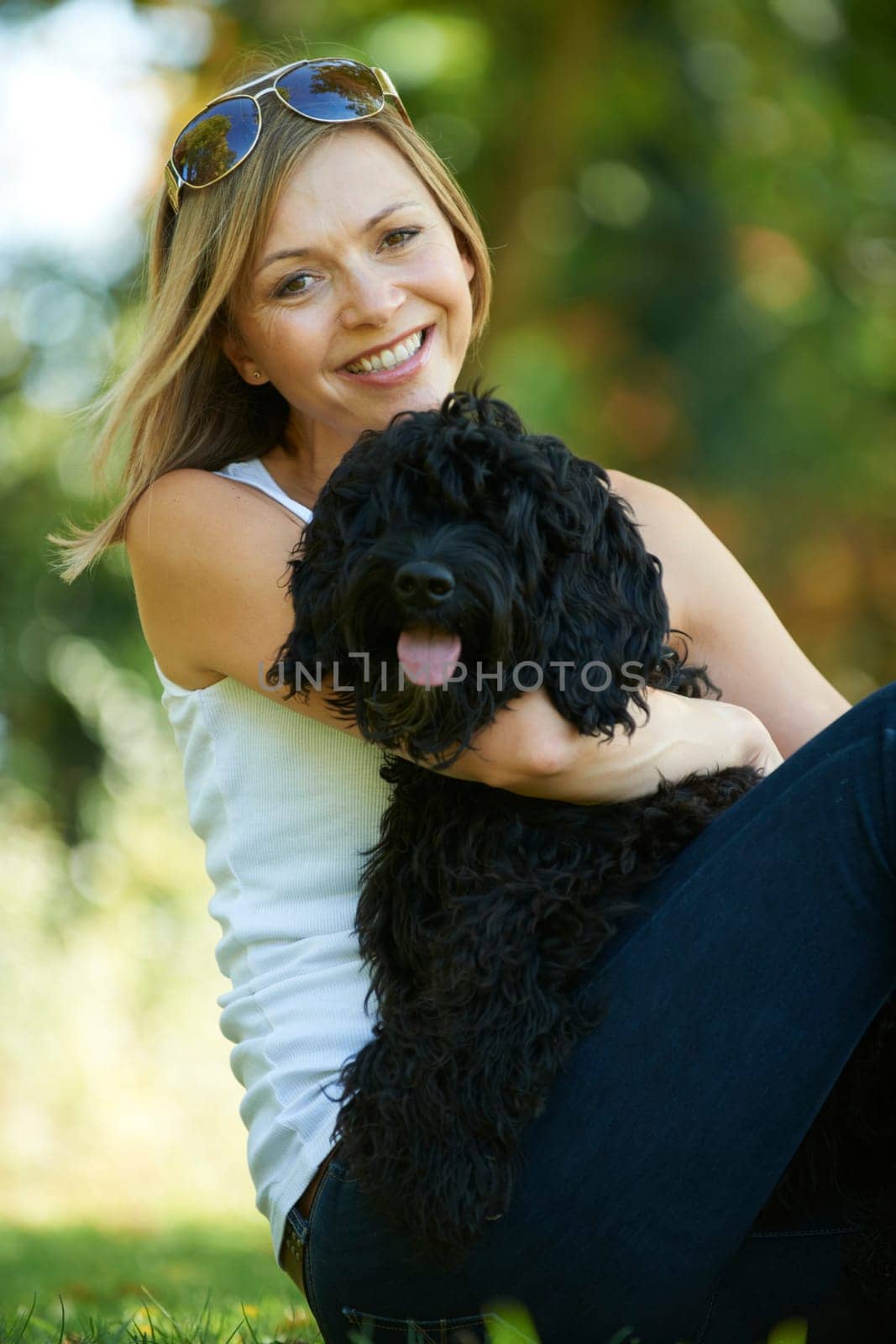 woman relaxing with black dog while on a walk in the park