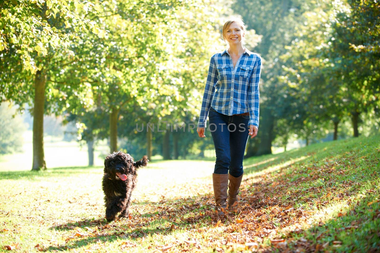 woman walking her black dog in the park on a sunny day