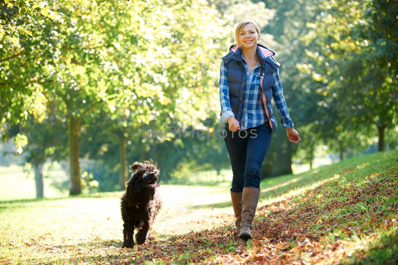 woman walking her black dog in the park on a sunny day