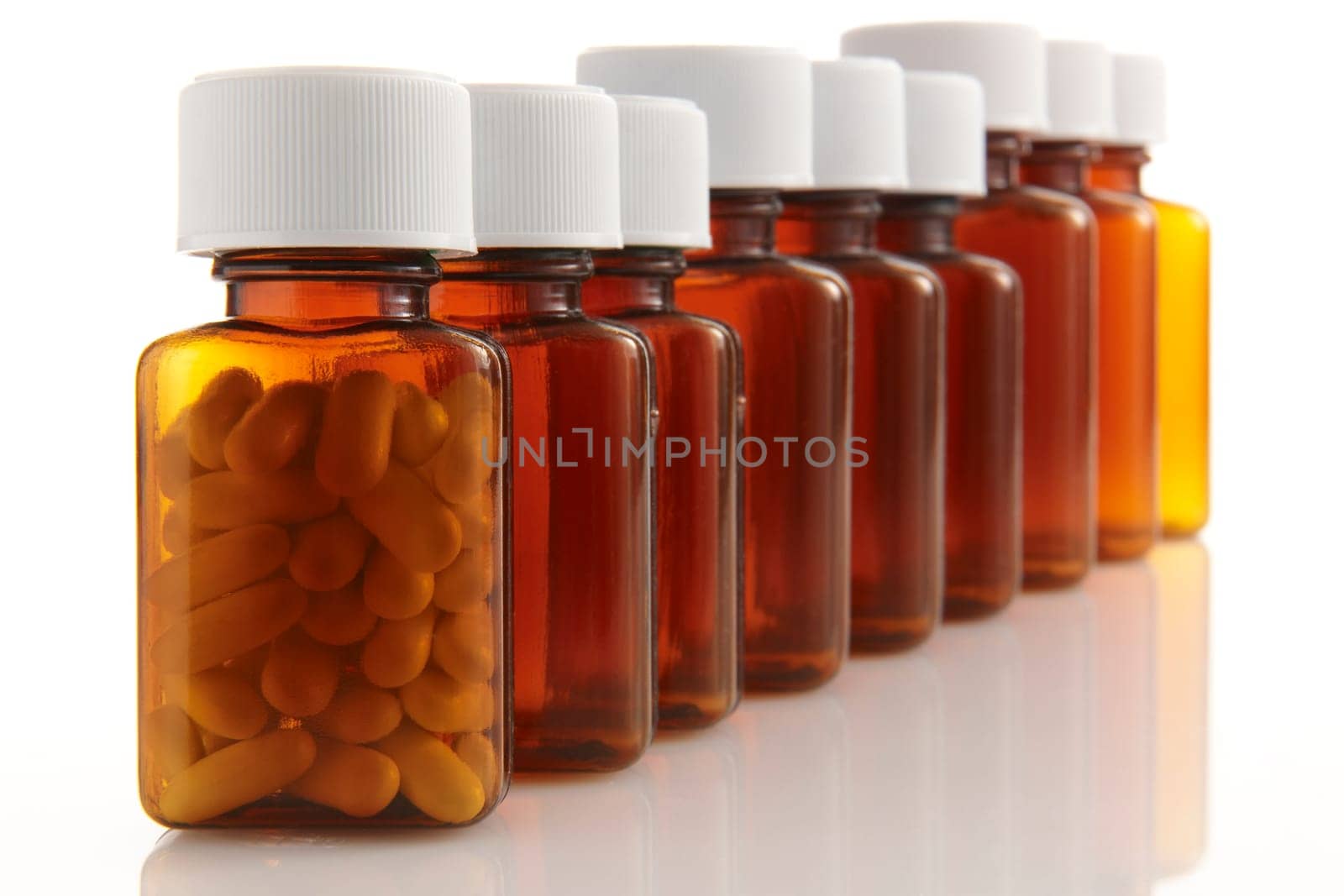 row of bottles with pills in the front container on white background