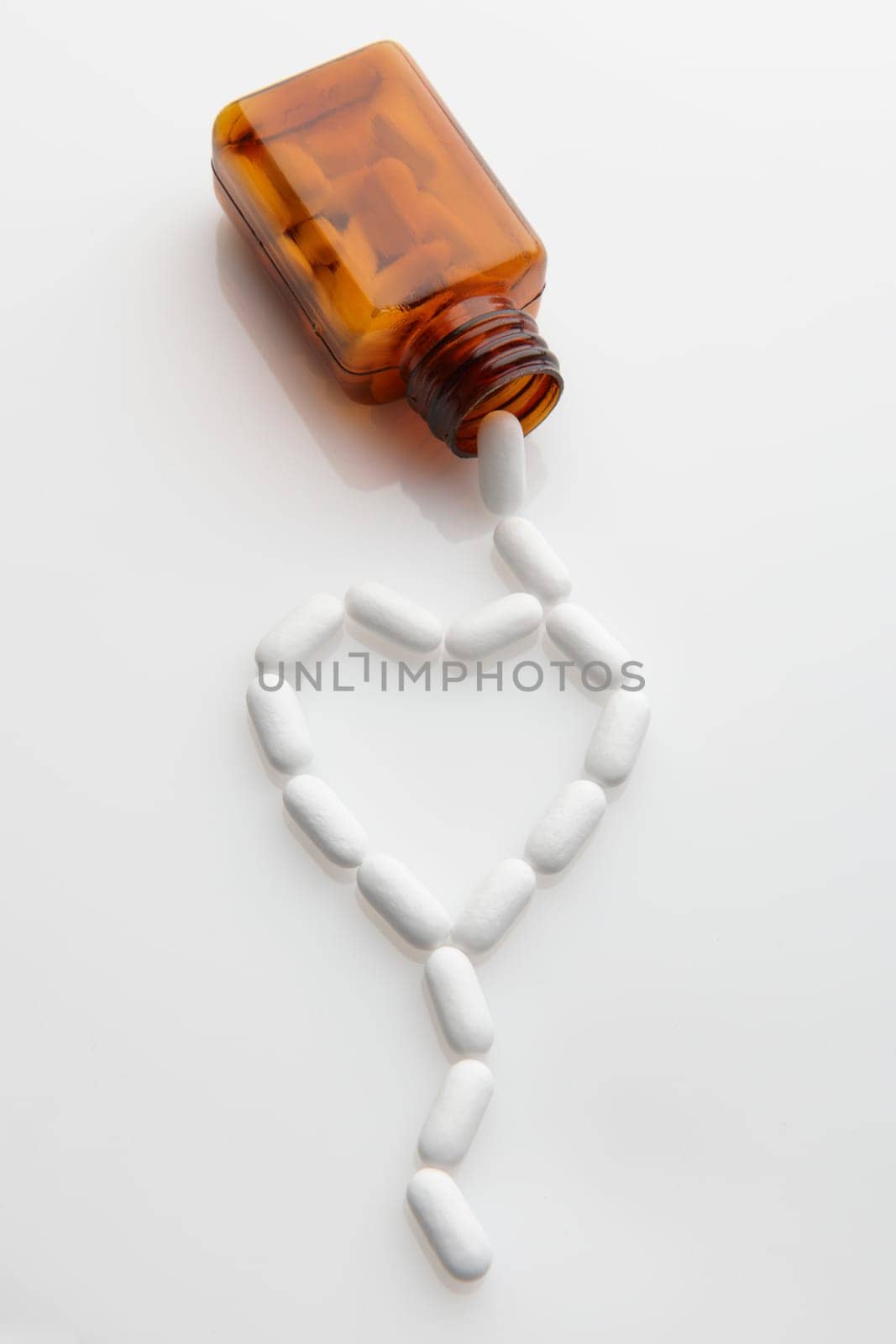 tablets coming out of bottle and forming shape of a heart