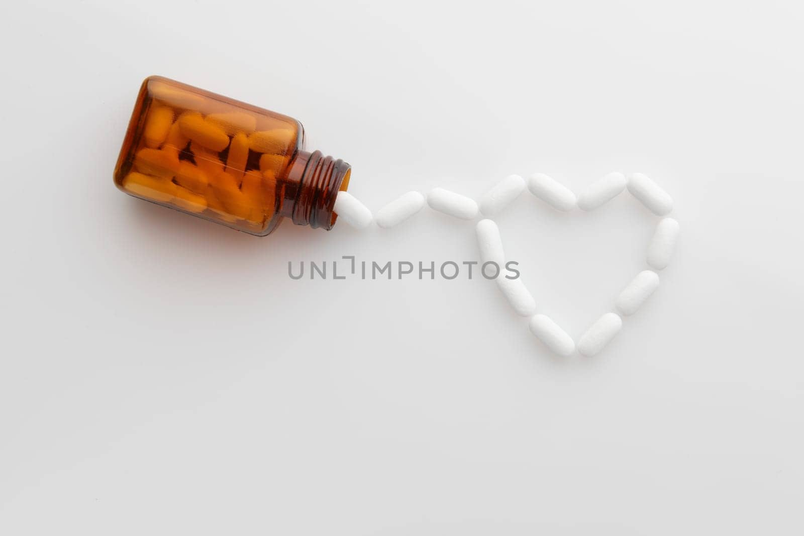 tablets coming out of bottle and forming shape of a heart