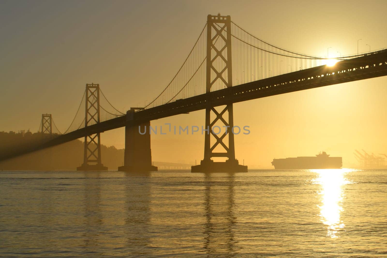 Bay Bridge at Sunrise with a container ship in the distance, San Francisco, California