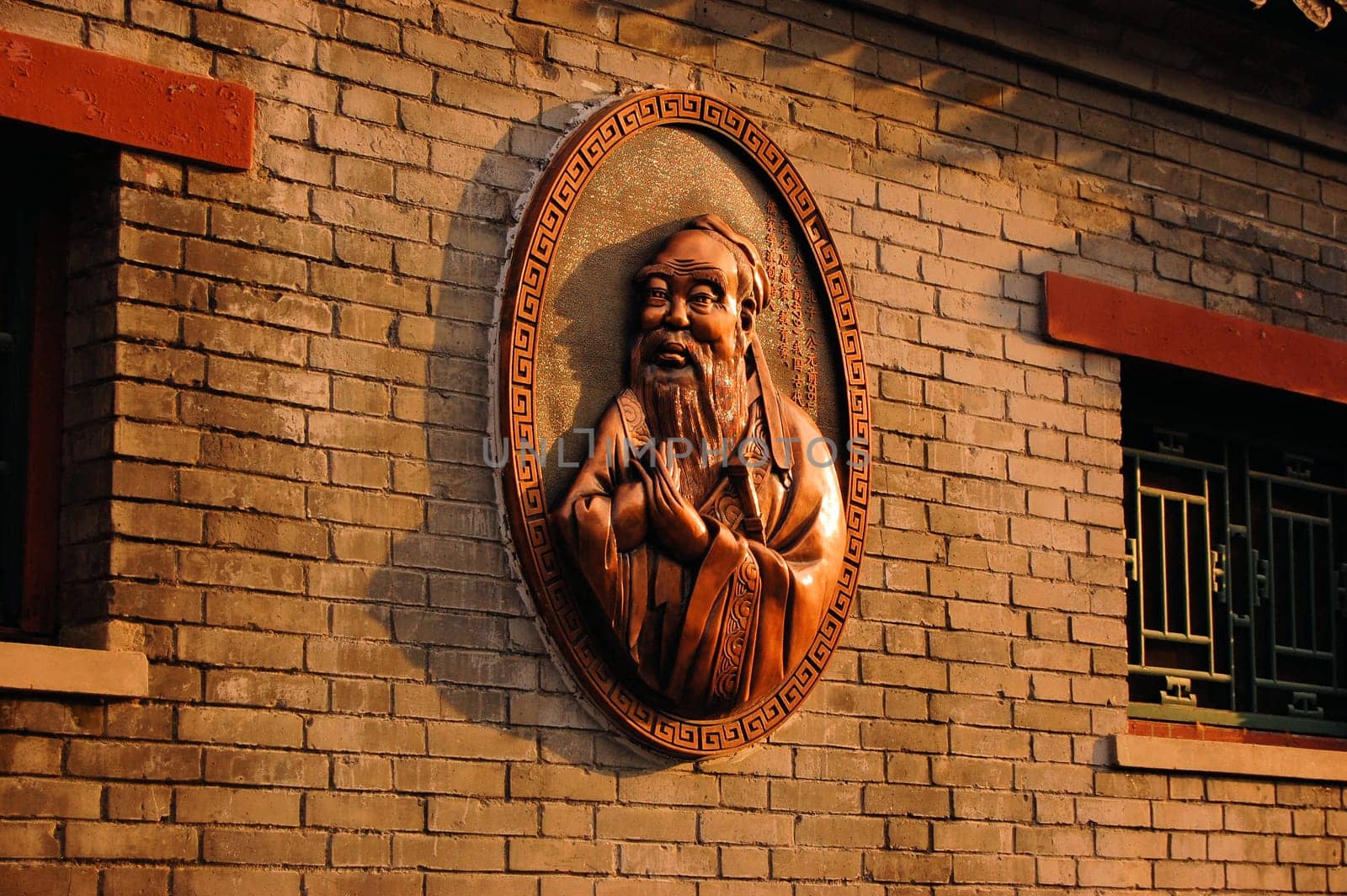 A bronze Statue of Confucius on the wall of a Confucius temple in Beijing, China