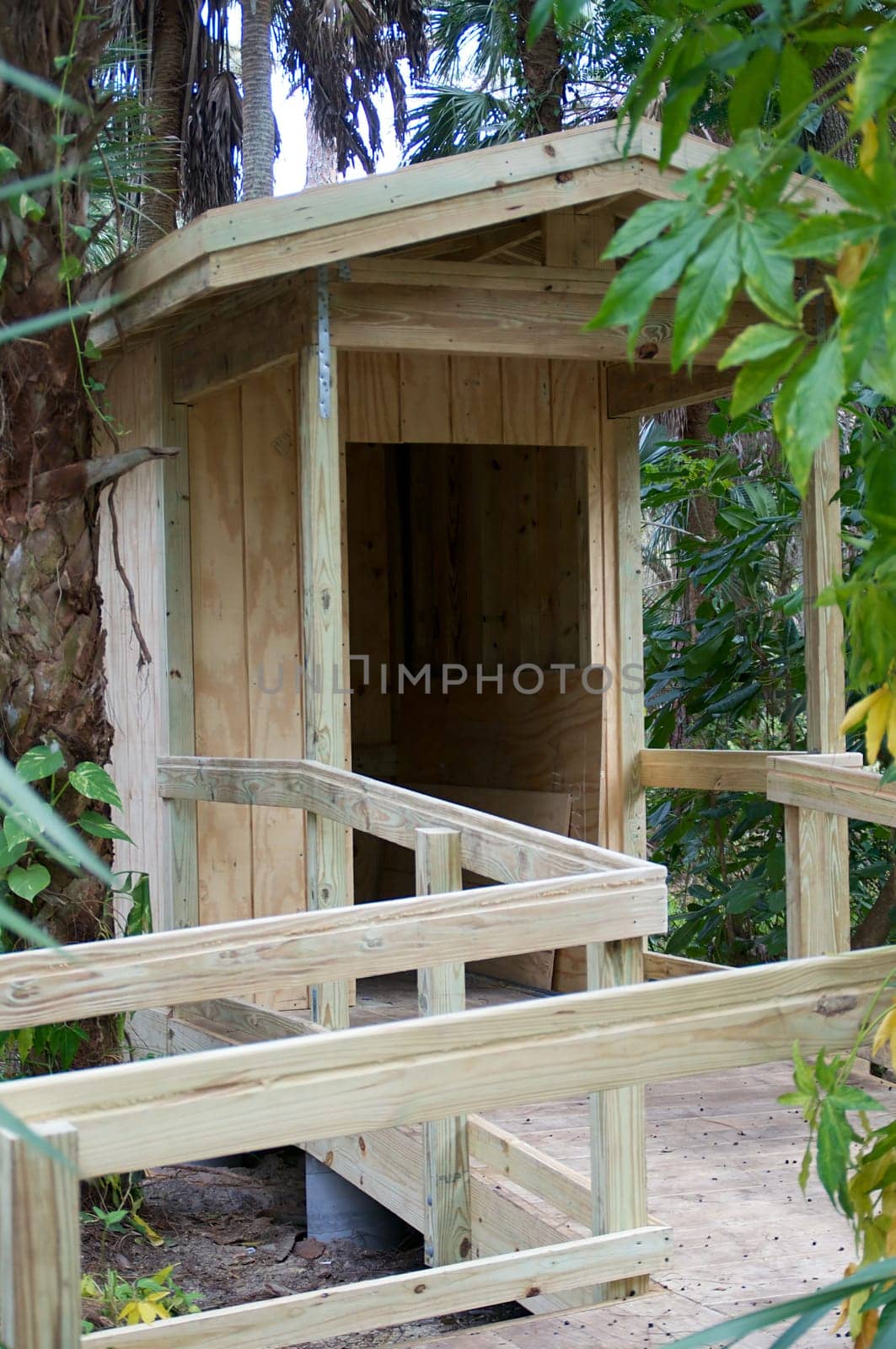 An almost completed shed made of wood with a ramp surrounded by trees.
